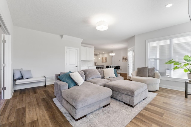 living room with light hardwood / wood-style flooring and a notable chandelier