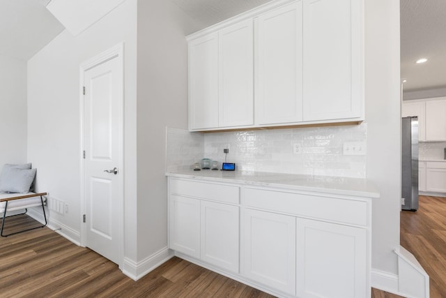 bar featuring dark wood-type flooring, backsplash, stainless steel fridge, a textured ceiling, and white cabinets