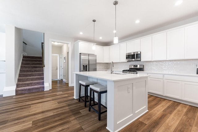 kitchen featuring a kitchen island with sink, white cabinetry, dark wood-type flooring, and appliances with stainless steel finishes