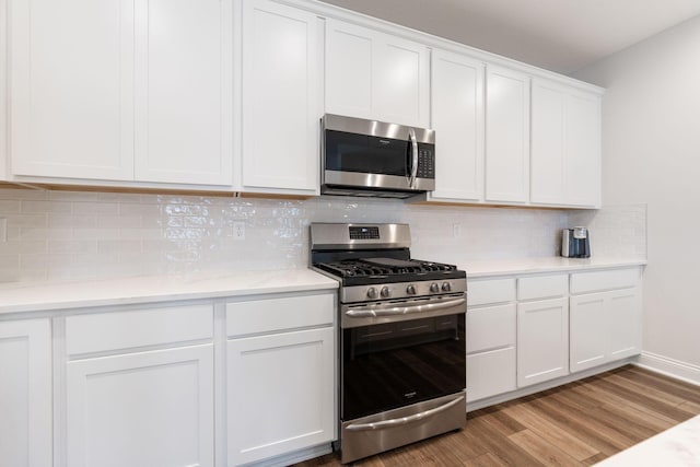 kitchen featuring white cabinets, stainless steel appliances, light hardwood / wood-style flooring, and tasteful backsplash