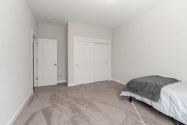 bedroom featuring light carpet, a closet, and a textured ceiling