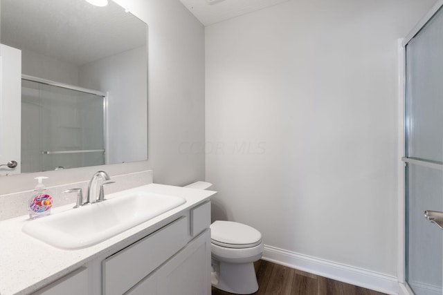 bathroom with hardwood / wood-style floors, vanity, toilet, and an enclosed shower