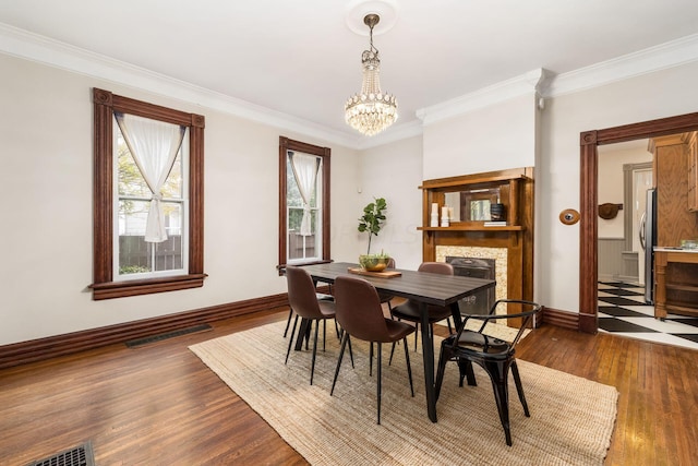 dining room with dark hardwood / wood-style flooring, ornamental molding, and a notable chandelier