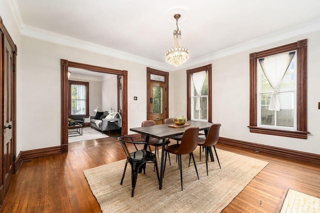 dining area with hardwood / wood-style floors, ornamental molding, and a notable chandelier