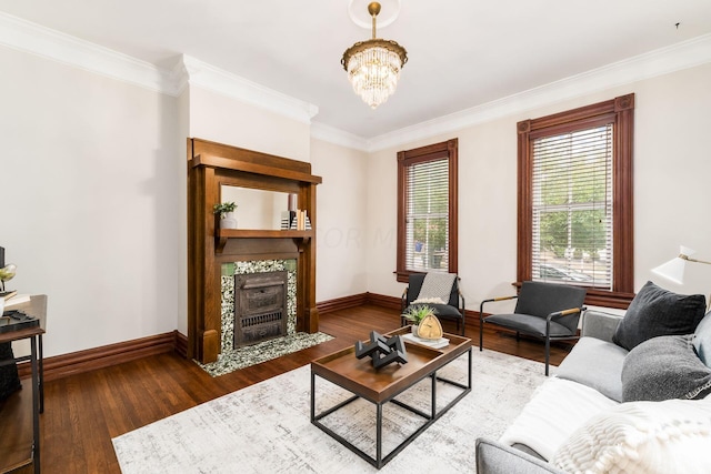 living room featuring a tile fireplace, ornamental molding, wood-type flooring, and an inviting chandelier