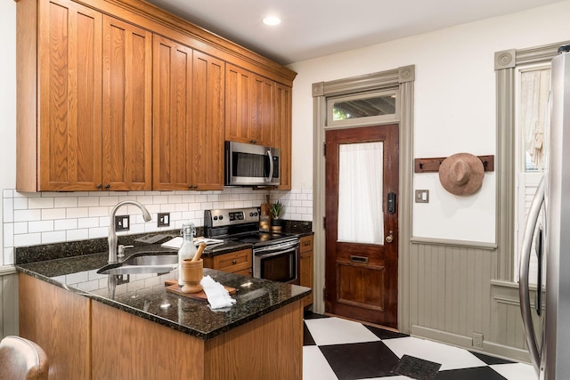 kitchen with sink, stainless steel appliances, kitchen peninsula, dark stone counters, and decorative backsplash