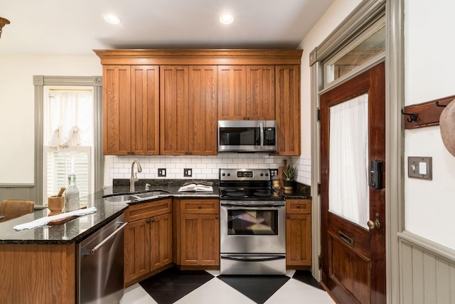 kitchen featuring backsplash, stainless steel appliances, dark stone countertops, and sink