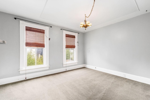 carpeted spare room with a notable chandelier