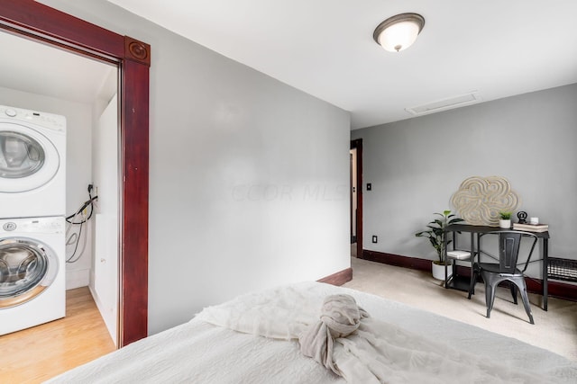 bedroom with hardwood / wood-style floors and stacked washing maching and dryer