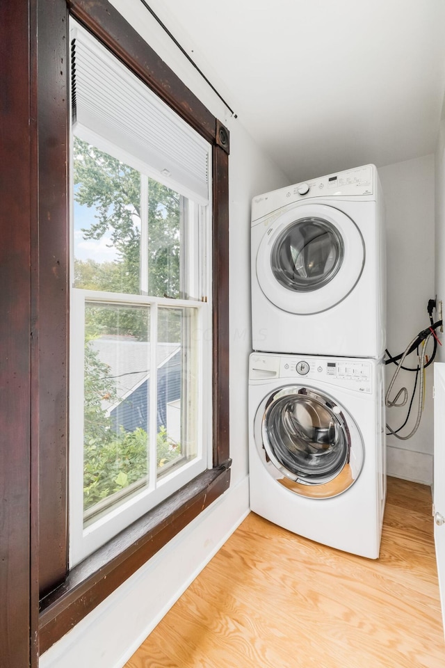 laundry room with light hardwood / wood-style floors and stacked washer / drying machine