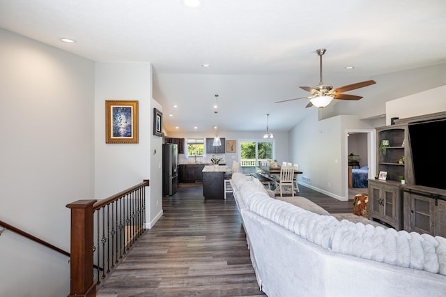 living room featuring vaulted ceiling, ceiling fan, and dark wood-type flooring