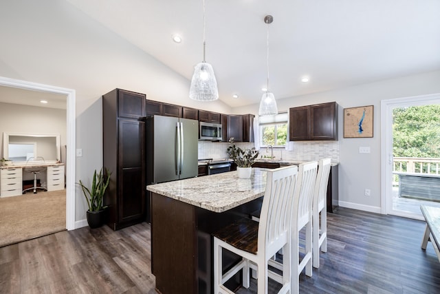 kitchen featuring pendant lighting, lofted ceiling, appliances with stainless steel finishes, a kitchen island, and dark hardwood / wood-style flooring