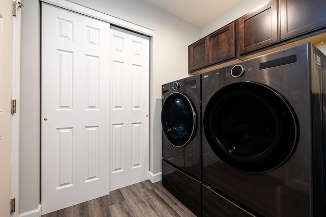 washroom with washer and clothes dryer, cabinets, and wood-type flooring