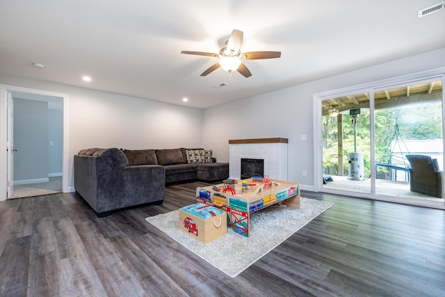 living room featuring a tiled fireplace, ceiling fan, and dark hardwood / wood-style flooring