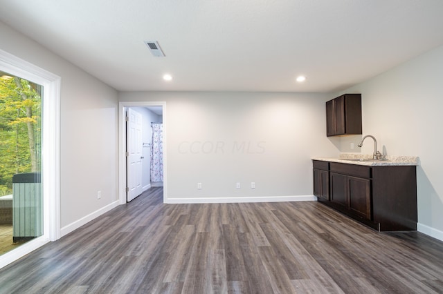 bar with sink, dark wood-type flooring, and dark brown cabinets