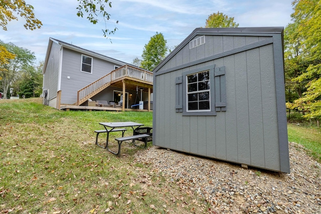 rear view of property with a lawn, an outbuilding, and a deck