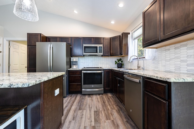 kitchen with decorative backsplash, appliances with stainless steel finishes, vaulted ceiling, decorative light fixtures, and light hardwood / wood-style flooring