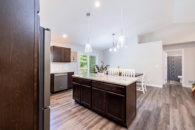 kitchen with a center island, hanging light fixtures, vaulted ceiling, light wood-type flooring, and stainless steel appliances