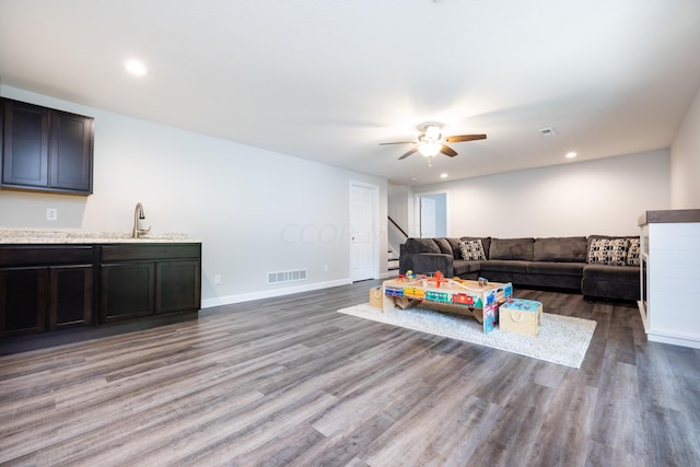 living room featuring hardwood / wood-style flooring, ceiling fan, and sink