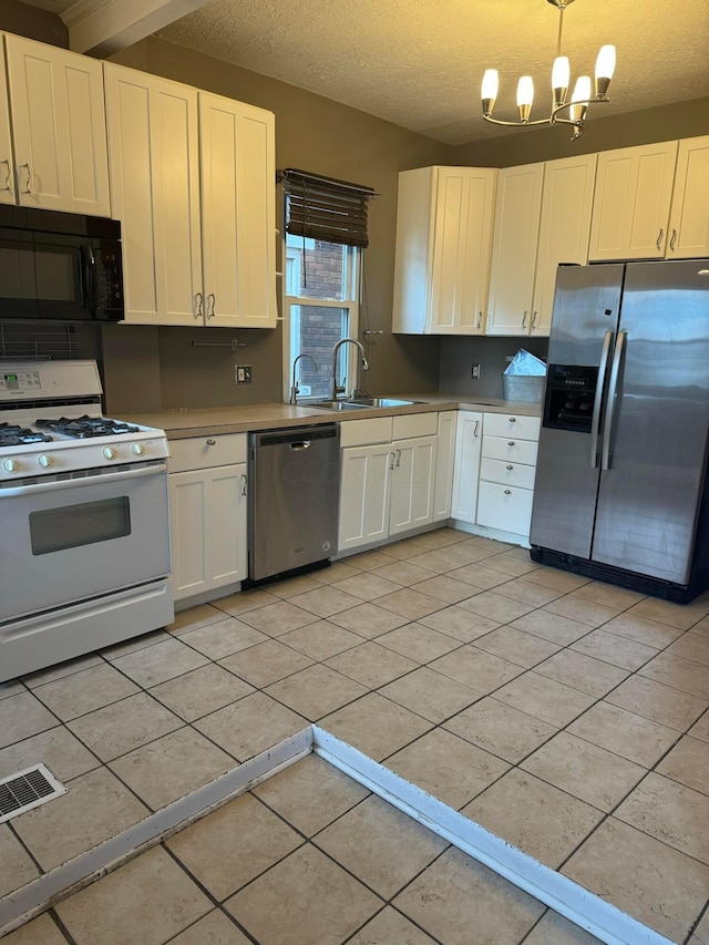 kitchen featuring appliances with stainless steel finishes, a textured ceiling, sink, decorative light fixtures, and white cabinetry