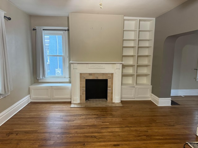 unfurnished living room featuring a fireplace and dark wood-type flooring