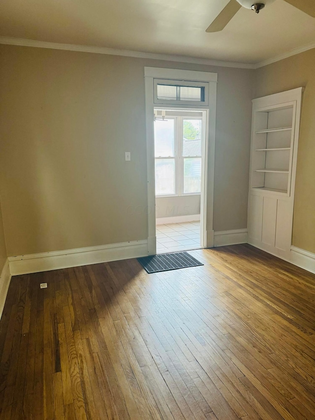 spare room with ceiling fan, light hardwood / wood-style floors, built in features, and crown molding