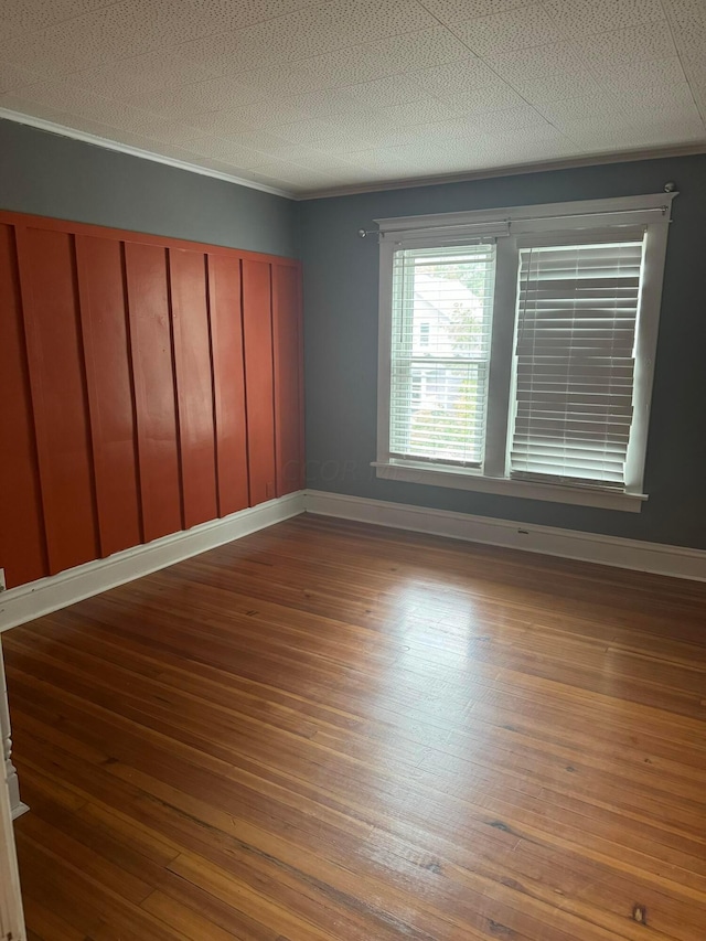 spare room featuring hardwood / wood-style flooring, crown molding, and a textured ceiling