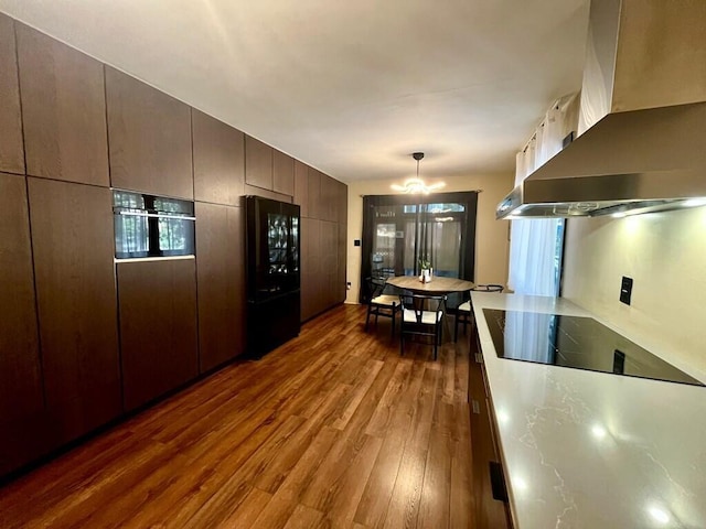 kitchen with dark hardwood / wood-style flooring, extractor fan, black appliances, decorative light fixtures, and an inviting chandelier