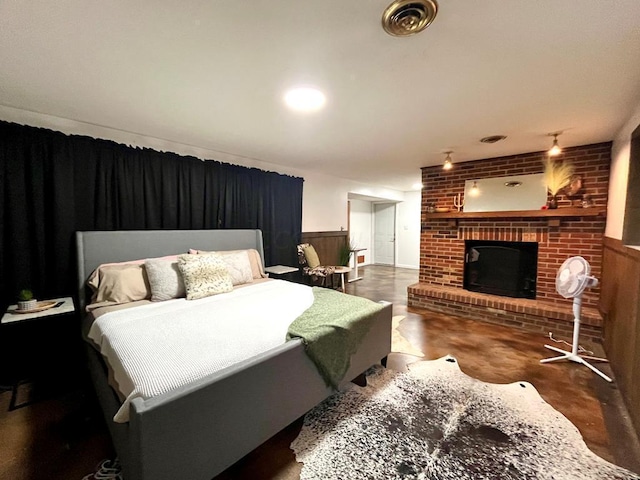 bedroom featuring wooden walls and a brick fireplace