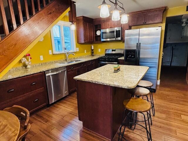 kitchen featuring pendant lighting, sink, light hardwood / wood-style flooring, appliances with stainless steel finishes, and a kitchen island