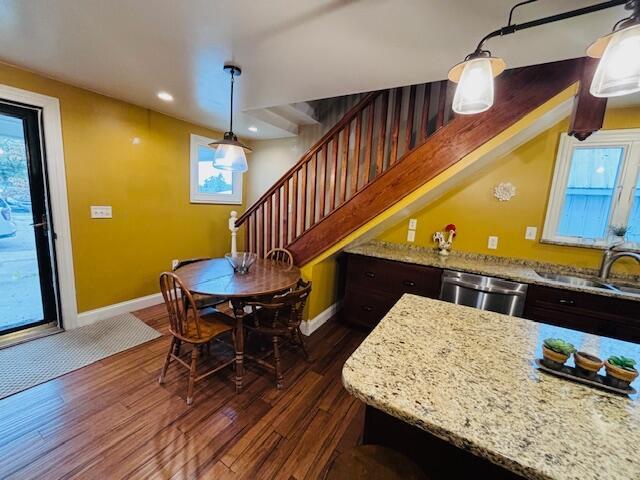 kitchen featuring pendant lighting, dark hardwood / wood-style flooring, stainless steel dishwasher, and sink