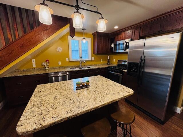 kitchen featuring dark hardwood / wood-style floors, a center island, hanging light fixtures, and appliances with stainless steel finishes