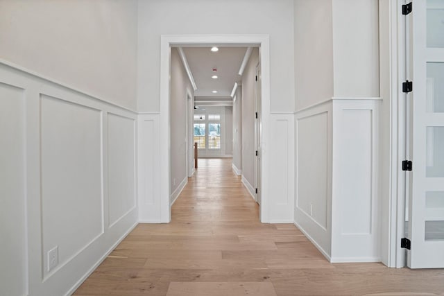 corridor with ornamental molding and light wood-type flooring