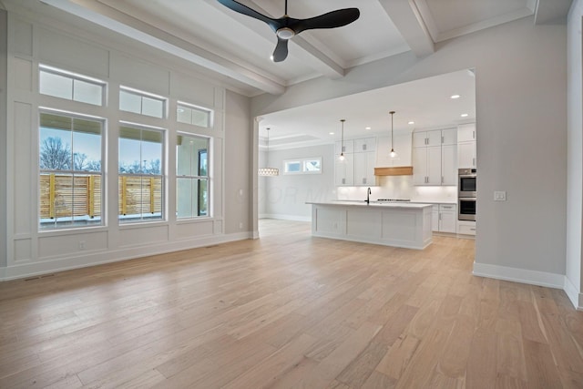 unfurnished living room featuring beam ceiling, ceiling fan, light wood-type flooring, and ornamental molding