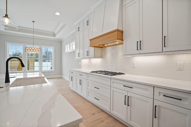 kitchen featuring sink, white cabinets, stainless steel gas stovetop, and pendant lighting