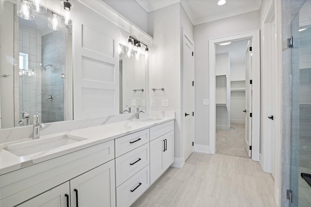 bathroom featuring vanity, a shower with shower door, and ornamental molding