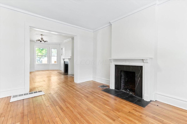 unfurnished living room featuring hardwood / wood-style floors, a notable chandelier, crown molding, and a tile fireplace