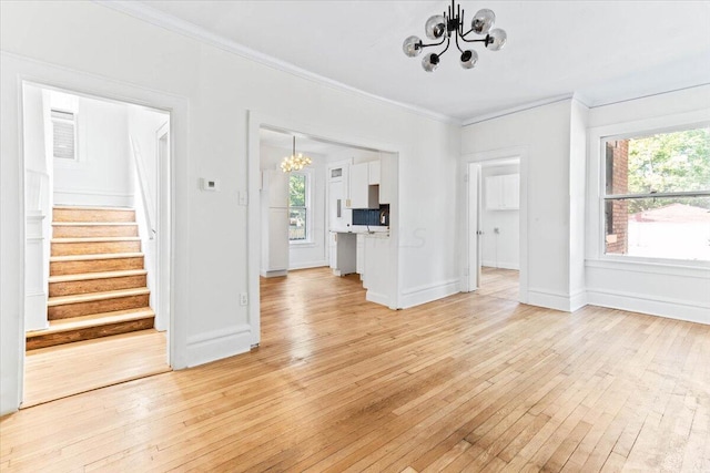 unfurnished living room featuring light hardwood / wood-style flooring, a chandelier, and ornamental molding