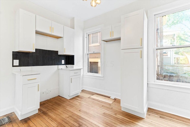 kitchen with backsplash, white cabinetry, and light hardwood / wood-style floors