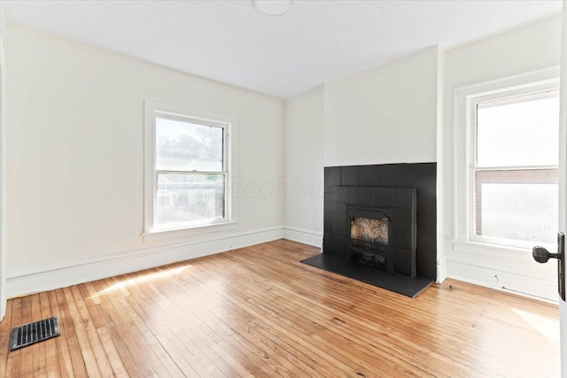 unfurnished living room with a tile fireplace and light hardwood / wood-style floors