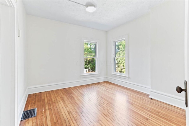 unfurnished room featuring a textured ceiling and light hardwood / wood-style flooring