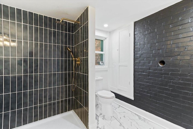 bathroom with a tile shower and toilet