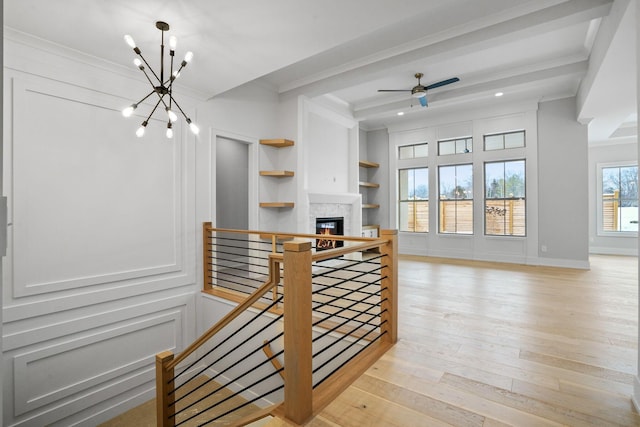 interior space with ceiling fan with notable chandelier, built in features, crown molding, and light hardwood / wood-style flooring