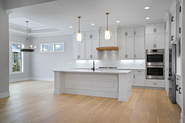 kitchen with white cabinets, an island with sink, and pendant lighting