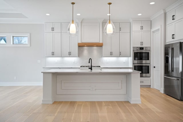 kitchen with white cabinets, a kitchen island with sink, hanging light fixtures, and appliances with stainless steel finishes