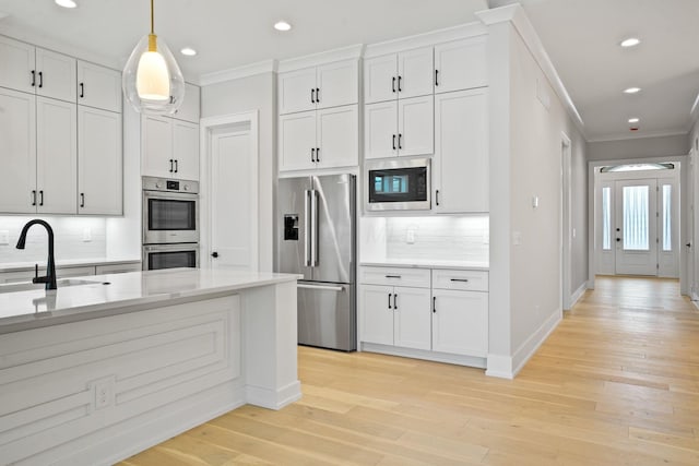 kitchen with sink, stainless steel appliances, tasteful backsplash, pendant lighting, and white cabinets