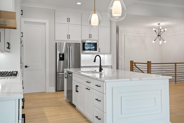 kitchen featuring a center island with sink, pendant lighting, white cabinetry, and appliances with stainless steel finishes