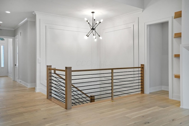 hallway featuring ornamental molding, light hardwood / wood-style flooring, and a notable chandelier