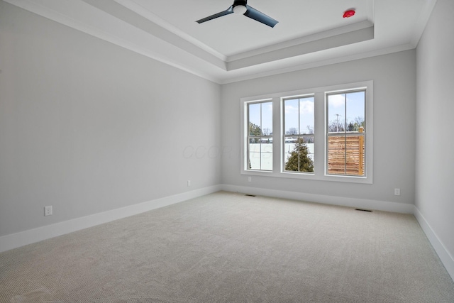 unfurnished room featuring a tray ceiling, ceiling fan, carpet flooring, and ornamental molding