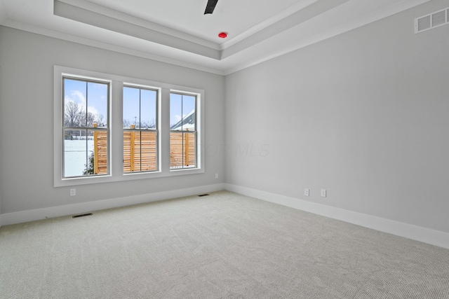 empty room featuring carpet, a tray ceiling, ceiling fan, and ornamental molding